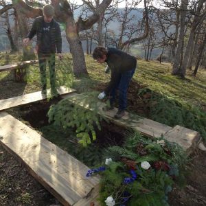 family and friends lay pine boughs in grave during natural burial