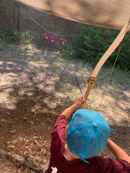 young boy prepares to shoot arrow at Great River archery range